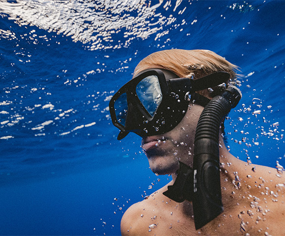 Mergulhador branco submerso no mar com máscara de mergulho e snorkel.